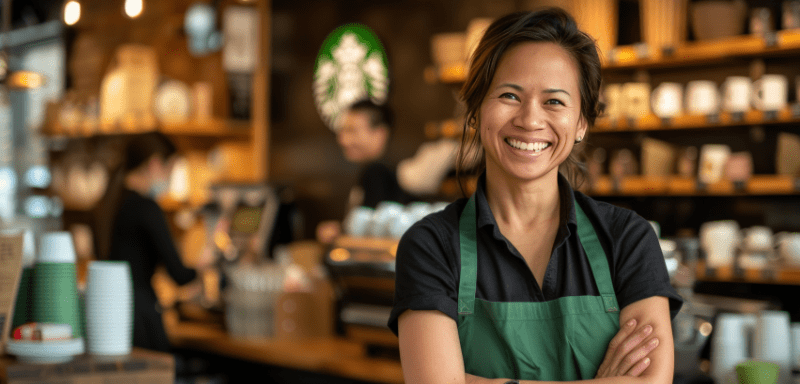 Atendente do Starbucks, em cafeteria, sorrindo.