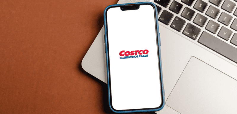 Logo da Costco em celular, sobre um laptop.