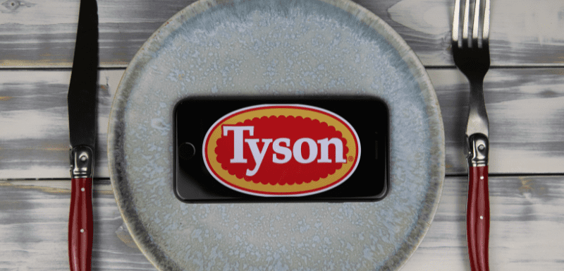 Logo da Tyson Foods em celular, sobre prato.